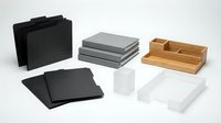Modern office desk organizers and storage boxes in black, gray, white and wood tones arranged on clean background for workspace organization solutions.