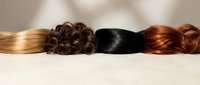 Collection of natural human hair extensions in various colors and textures including blonde, brunette, black and auburn shades for salon styling.