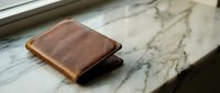Brown leather wallet on marble surface showcasing craftsmanship and luxury accessories for business and personal use.
