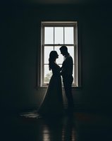 Romantic couple silhouettes embracing by window in dramatic lighting for wedding photography and love concepts.