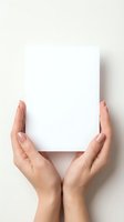 Hands holding blank white card on neutral background, suitable for mockups, presentations, advertising campaigns, and promotional materials.