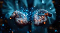 Magical glowing blue sparkles and light particles floating above cupped hands against dark background, creating mystical atmosphere for spiritual and wellness concepts.