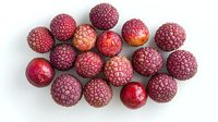 Fresh ripe lychee fruits scattered on white background, exotic tropical asian fruit with red rough skin and sweet flesh, isolated food photography.