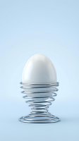 White egg in metal wire holder on light blue background for kitchen and cooking concepts.