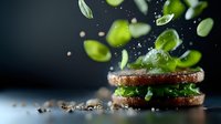 Levitating fresh green ingredients and spices above burger buns with water drops and motion blur effect on dark background, food photography.