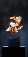 Abstract golden metallic sculpture floating above dark pedestal against moody background, featuring fluid organic curves and dynamic movement in copper tones.