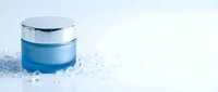 Blue cosmetic jar with silver lid surrounded by sparkling crystals and ice particles on white background, suitable for skincare and beauty product packaging design.