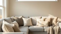 Modern neutral living room interior with comfortable gray sectional sofa, decorative pillows and soft natural lighting for home decor and lifestyle.