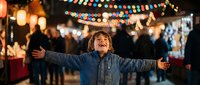 Happy young boy with arms outstretched enjoying festive evening at outdoor market with colorful string lights and warm bokeh background atmosphere.