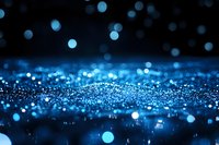 Magical blue glitter sparkles on dark background with bokeh effect and defocused light particles creating dreamy abstract festive atmosphere.