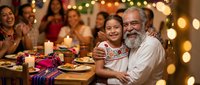 Multi-generational Hispanic family celebrating together at dinner table with warm lighting, grandfather hugging granddaughter during festive meal gathering.