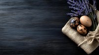 Rustic Easter composition with speckled quail eggs and dried lavender on burlap cloth against dark wooden background for spring holiday decorating.