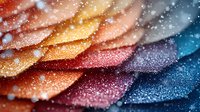 Macro photography of colorful flower petals with water droplets and sparkles creating dreamy bokeh effect in orange, red, blue and purple gradient tones.