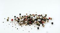 Mixed peppercorns blend with black white pink green varieties scattered on white background for culinary seasoning and cooking applications.