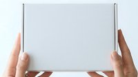 Two hands with light skin tone holding a blank white tablet or clipboard against a neutral background, suitable for mockups, presentations, and digital device advertising.