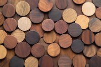 Round wooden discs in various natural brown shades arranged in geometric pattern creating textural background with warm tones and circular shapes.