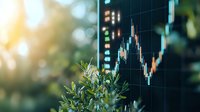 Green plant leaves in foreground with blurred stock market candlestick chart display in background showing financial data analysis and trading concept.