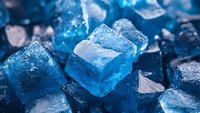 Macro view of blue crystal mineral formation with faceted surfaces and geometric shapes, showcasing natural geological structure in vibrant azure tones.