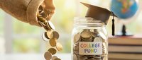Hand pouring coins into glass jar labeled college fund with graduation cap on top, books and globe in background representing education savings planning.