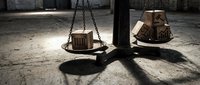 Vintage brass scales of justice with wooden boxes in dramatic lighting on concrete floor symbolizing legal balance and fairness in courtroom or law office setting.