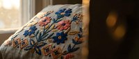 Traditional embroidered floral pattern on fabric with colorful threads creating decorative botanical design for textile and craft projects.