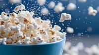 Fresh popcorn flying out of blue ceramic bowl against dark background with bokeh lights, dynamic food photography capturing motion and texture.