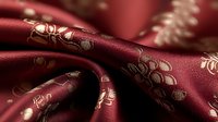 Luxurious burgundy silk fabric with golden floral embroidery draped elegantly, showcasing rich textile patterns for fashion design and home decor projects.