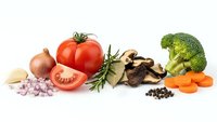 Fresh organic vegetables and herbs arranged on white background including tomatoes, broccoli, carrots, onions, garlic, mushrooms and spices for healthy cooking.