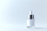 Elegant white glass dropper bottle with silver cap on light background, minimalist cosmetic packaging for skincare and beauty products presentation.