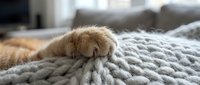 Young golden retriever puppy resting on gray knit blanket indoors, cozy home setting, pet comfort and relaxation concept.