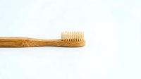 Eco-friendly bamboo toothbrush with natural bristles isolated on white background for sustainable oral hygiene and zero waste lifestyle.