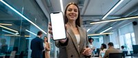Young professional businesswoman holding blank smartphone screen in modern office environment for mobile app presentation and digital marketing campaigns.