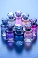 Small glass bottles with colorful liquid in purple, blue, and pink tones arranged in circle on wet surface with dramatic lighting and reflections.
