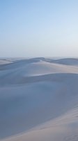 Serene desert landscape with undulating white sand dunes under soft morning light, showcasing smooth curves and shadows for travel, nature, and background design projects.