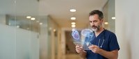 Middle-aged Caucasian male doctor in navy scrubs examining X-ray film in modern hospital corridor with professional lighting and clean medical environment.