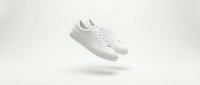 White sneakers floating on neutral beige background with soft shadow. Clean minimalist footwear design for fashion, lifestyle and product advertising.
