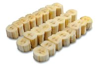 Fresh sliced banana pieces arranged in neat rows on white background, showing cross-sections with natural pattern. Isolated food photography for culinary designs.