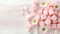 Pink marshmallows and fresh daisies on white wooden background, soft pastel composition with copy space for sweet food design and romantic styling.