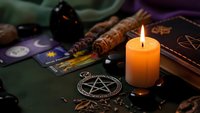 Mystical witchcraft altar with burning candle, tarot cards, pentagram, crystals and magical tools for spiritual divination and occult practices.