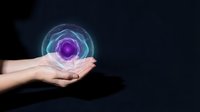 Human hands holding glowing purple energy sphere with swirling light effects against dark background for spiritual healing and meditation concepts.