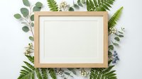 Wooden frame with white mat surrounded by fresh green ferns, eucalyptus leaves, and white flowers on neutral background. Perfect for home decor, botanical designs, and nature-themed projects.