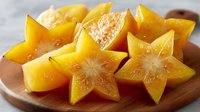 Fresh star fruit slices arranged on wooden cutting board showing tropical carambola's distinctive five-pointed star shape and golden yellow color.