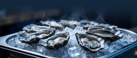 Fresh raw oysters on ice platter ready for serving at seafood restaurant or gourmet dining experience with dark moody background lighting.