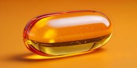 Transparent amber gel capsule with liquid medicine on orange background, showcasing pharmaceutical supplement in close-up detail.