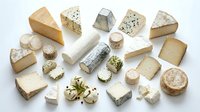 Assorted artisanal cheese varieties including aged cheddar, blue cheese, goat cheese and soft cheeses arranged on white background for food styling and culinary projects.