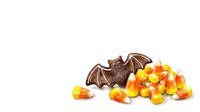 Chocolate bat figure surrounded by candy corn isolated on white background, ready for Halloween design projects, clipart, and seasonal marketing materials.