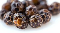 Aromatic black peppercorns macro shot showing detailed texture and pattern of dried spice on white background, natural food ingredient for cooking.