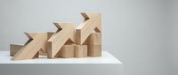 Wooden blocks arranged as ascending arrow chart showing business growth and success concept on white surface against gray background.