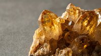 Cluster of golden amber crystals with translucent facets and warm honey tones against neutral background, suitable for geology, mineral collection, and natural science educational materials.