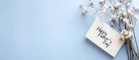 White gypsophila flowers with Happy Father's Day greeting card on light blue background. Minimal holiday composition with copy space for text.